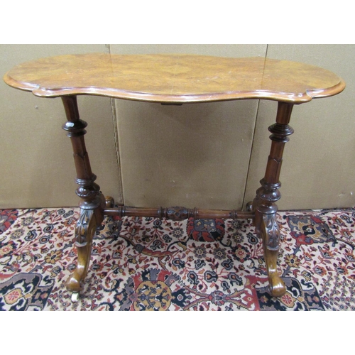 3601 - A Victorian walnut and figured walnut occasional table with shaped outline, raised on a stretcher ba... 