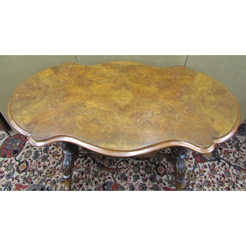 3601 - A Victorian walnut and figured walnut occasional table with shaped outline, raised on a stretcher ba... 