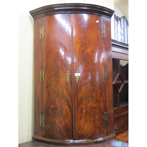 3539 - A Regency mahogany bowfronted hanging corner cupboard enclosed by a pair of well matched flamed door... 