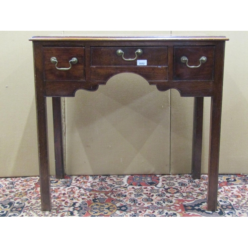 3552 - A Georgian mahogany lowboy fitted with three drawers to a central kneehole, on square cut supports