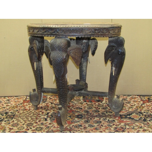 3554 - An Indian hardwood occasional table the circular top with repeating detail, raised on four elephant ... 