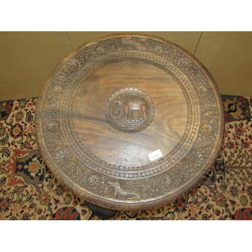 3554 - An Indian hardwood occasional table the circular top with repeating detail, raised on four elephant ... 