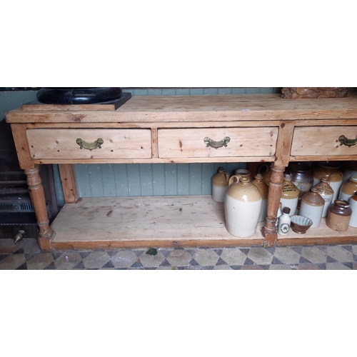 3022 - A large pine stripped dresser base enclosing four frieze drawers raised on turned supports with pot ... 