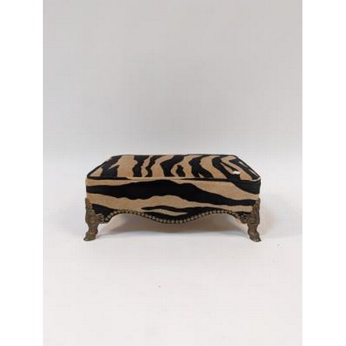 2741 - A rectangular footstool with Zebra print upholstery, on gilt hoof feet, 43cm wide