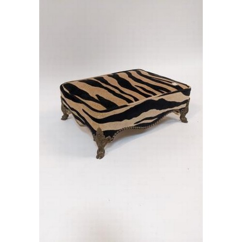 2741 - A rectangular footstool with Zebra print upholstery, on gilt hoof feet, 43cm wide