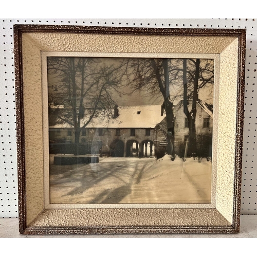 106 - Black and white printed photograph of a snowy courtyard with four frames including carved wood and o... 