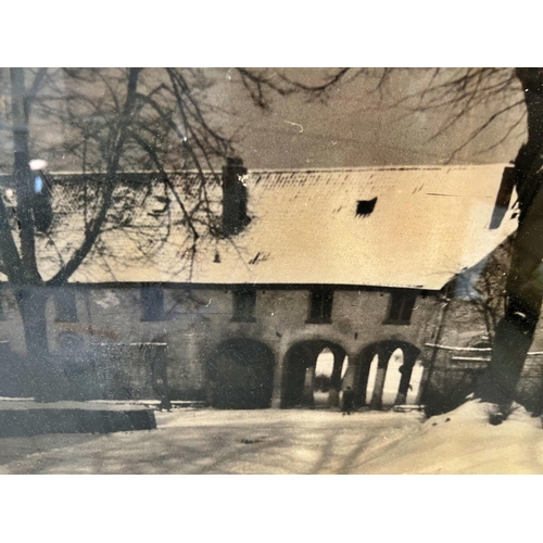 106 - Black and white printed photograph of a snowy courtyard with four frames including carved wood and o... 