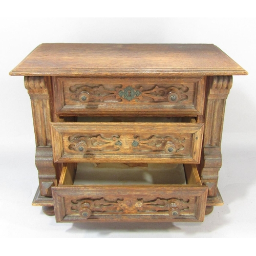 1464 - A miniature oak chest of with three carved panelled drawers, on bun feet, 30cm wide x 24cm high.