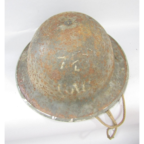 1487 - A rusty military tin helmet with original head padding and chin strap and a crude curved dagger in a... 