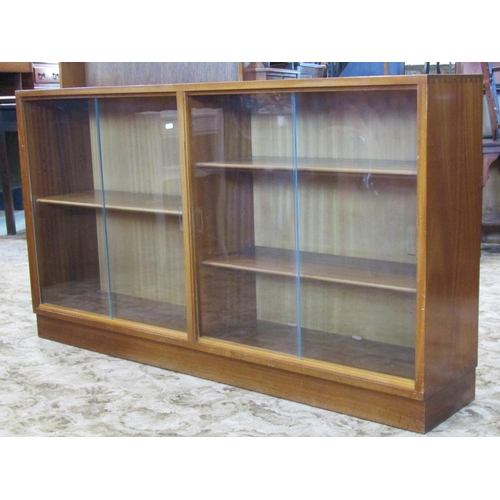 2743 - A mid 20th century side by side bookcase enclosed by two pairs of plate glass sliding doors, with ad... 