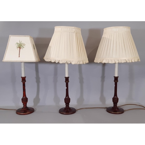 1526 - Three red and black marble effect painted candlestick table lamps, each with a shade.