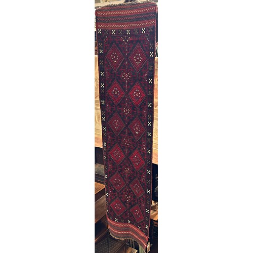 1583 - A Meshwani Runner with repeating rows of diamonds mainly red and blue on a black ground, 243cm x 60c... 