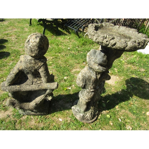 2074 - A weathered cast composition stone two sectional bird bath, the pedestal in the form of a man beside... 