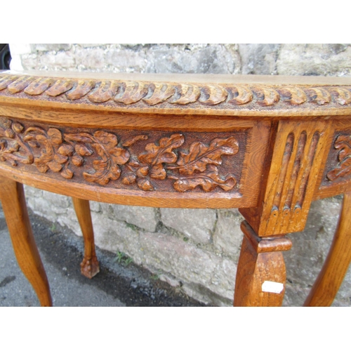 2148 - An oak demi-lune side table with carved border and frieze raised on shaped supports with claw and ba... 