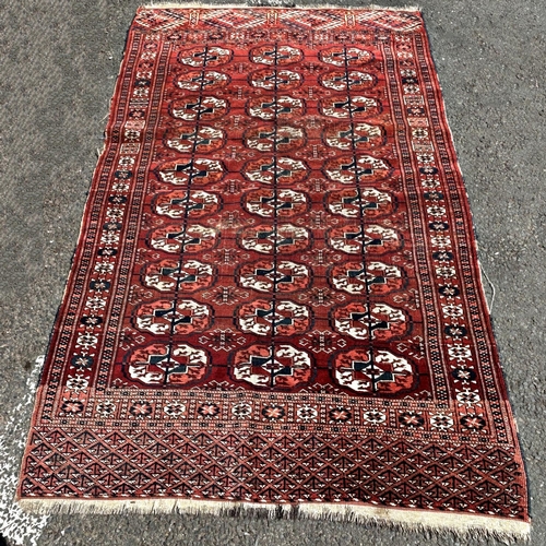 1589 - An old slightly worn Turkoman rug with three rows of elephant foot guls, in red hues, 193cm x 117cm ... 