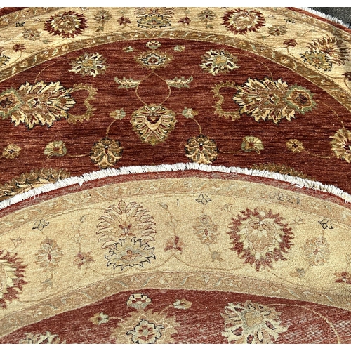 1590 - A circular Zeigler carpet with a central brown circular panel with an all over floral pattern, and a... 