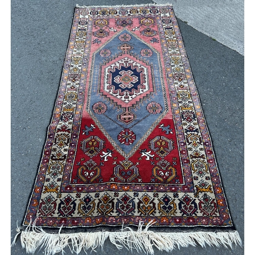 1606 - A Kazak carpet with n elongated stepped lozenge medallion and a stylised floral border, 220cm x 105c... 