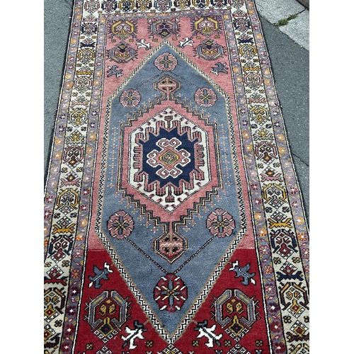 1606 - A Kazak carpet with n elongated stepped lozenge medallion and a stylised floral border, 220cm x 105c... 