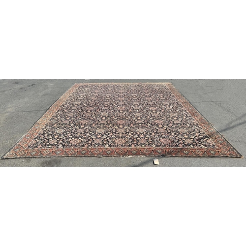 1610 - A large Middle Eastern style carpet with an all over floral pattern on a black field (repaired and s... 