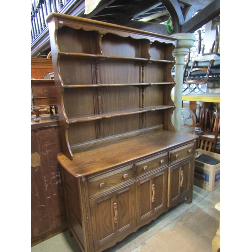 2197 - An Ercol oak dresser, the base enclosed by three panelled doors and three drawers, the plate rack wi... 