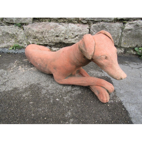 2076 - A cast composition stone garden ornament in the form of a recumbent hound, 60cm long x 25cm high