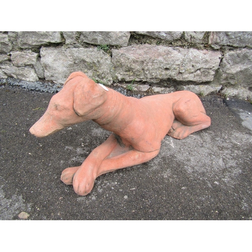 2076 - A cast composition stone garden ornament in the form of a recumbent hound, 60cm long x 25cm high