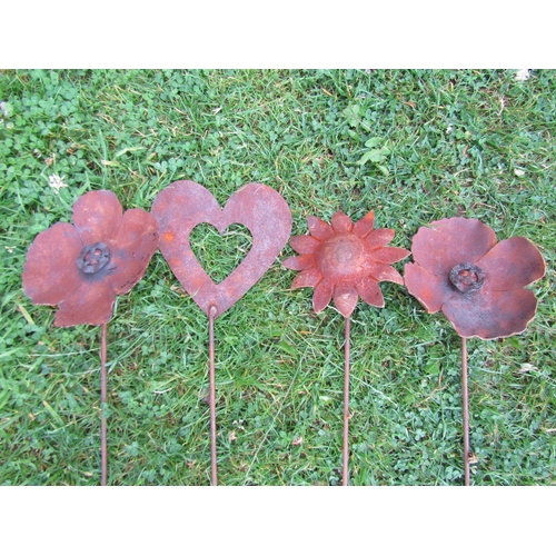 Four weathered steel ornamental garden border stakes comprising two poppy. sunflower and a heart shaped example