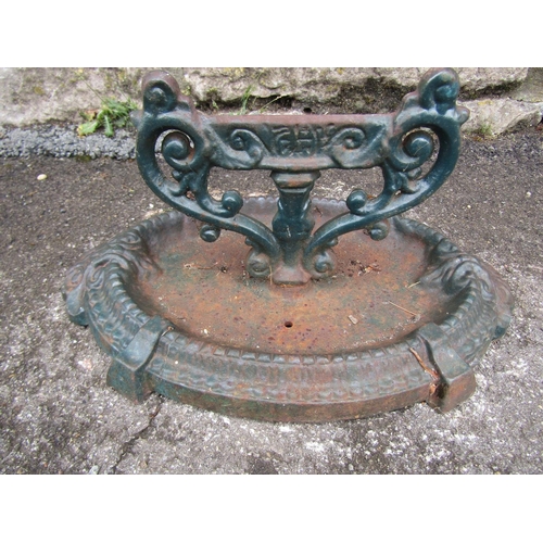 2073 - A cast iron boot scraper with scrolling canthus detail and oval tray base, 18cm high, the tray base ... 