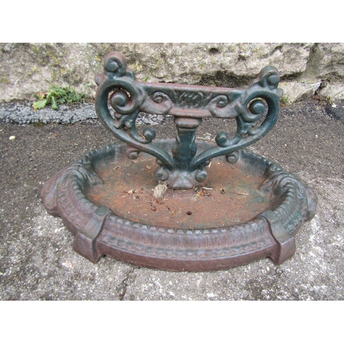 2073 - A cast iron boot scraper with scrolling canthus detail and oval tray base, 18cm high, the tray base ... 