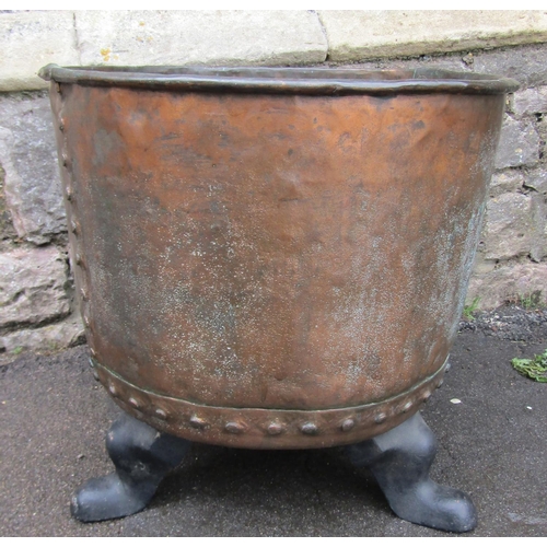 2081 - An antique copper with rolled rim and pop riveted seams, raised on later cast iron swept feet, 56cm ... 