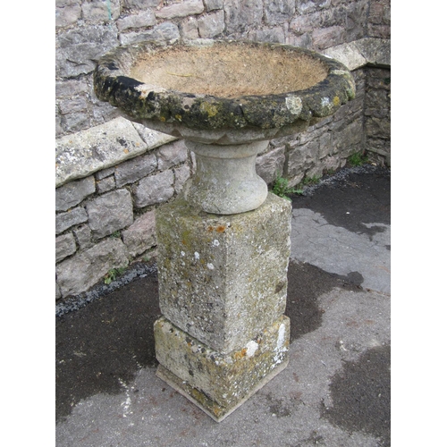 2086 - A weathered natural stone garden urn, the shallow circular carved bowl raised on a loose socle and s... 