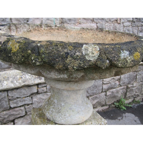 2086 - A weathered natural stone garden urn, the shallow circular carved bowl raised on a loose socle and s... 