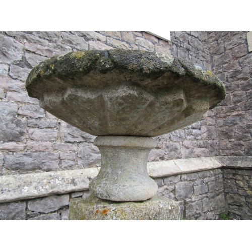 2086 - A weathered natural stone garden urn, the shallow circular carved bowl raised on a loose socle and s... 