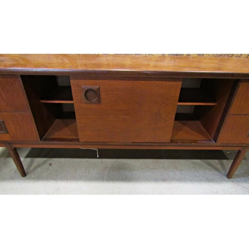 2195 - A long and low mid 20th century teak sideboard partially enclosed by a pair of central sliding doors... 