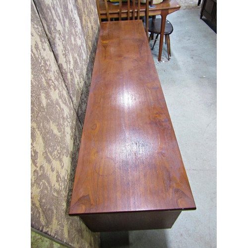 2195 - A long and low mid 20th century teak sideboard partially enclosed by a pair of central sliding doors... 