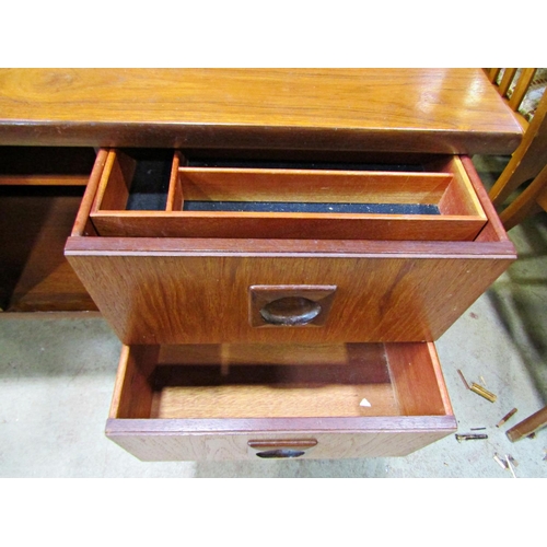 2195 - A long and low mid 20th century teak sideboard partially enclosed by a pair of central sliding doors... 