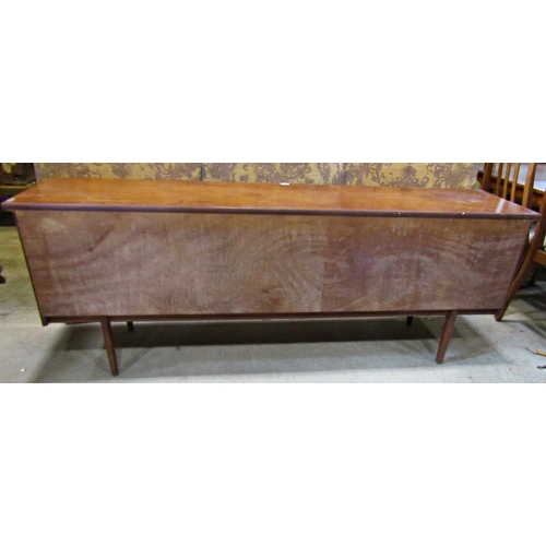 2195 - A long and low mid 20th century teak sideboard partially enclosed by a pair of central sliding doors... 