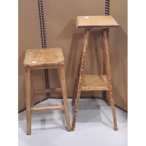 2219 - A vintage elm and beechwood stool with saddle shaped seat, together with a bamboo two tier plant sta... 