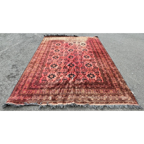 1684 - A large Persian style carpet with multi-geometric pattern on a red ground (faded in places) 340 cm x... 