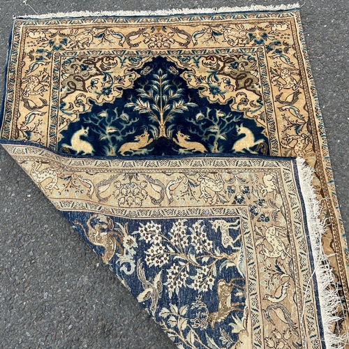 1685 - A Middle Eastern carpet with a garden scene of deer amongst flora on a dark blue ground 150 cm x 105... 