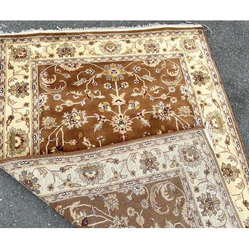 1687 - A Ziegler design carpet with scrolled flowers on a brown ground with running floral borders 181 cm x... 