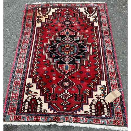 1694 - A Kazak design rug with a central stepped medallion on a red and green ground (stained in one corner... 