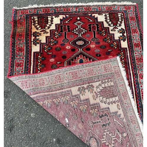 1694 - A Kazak design rug with a central stepped medallion on a red and green ground (stained in one corner... 