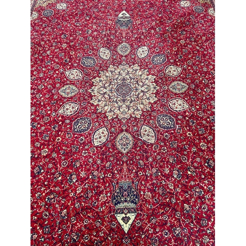 1695 - A large Wilton type carpet with a Persian design of a central medallion on a field of flowers on a r... 