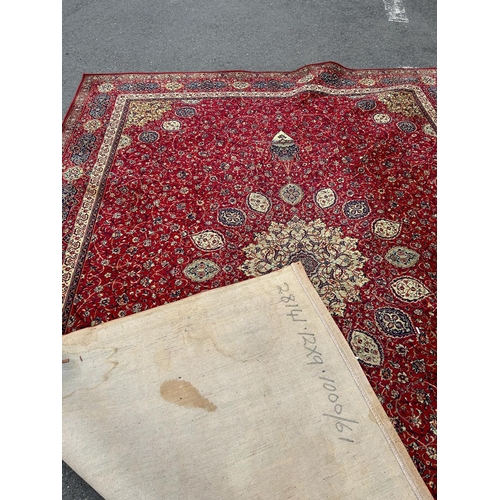 1695 - A large Wilton type carpet with a Persian design of a central medallion on a field of flowers on a r... 