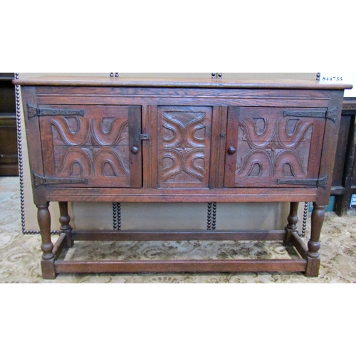 2335 - A rustic carved oak sideboard enclosed by two panelled doors with ironwork hinges on turned supports... 