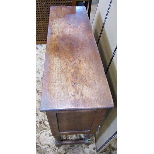 2335 - A rustic carved oak sideboard enclosed by two panelled doors with ironwork hinges on turned supports... 