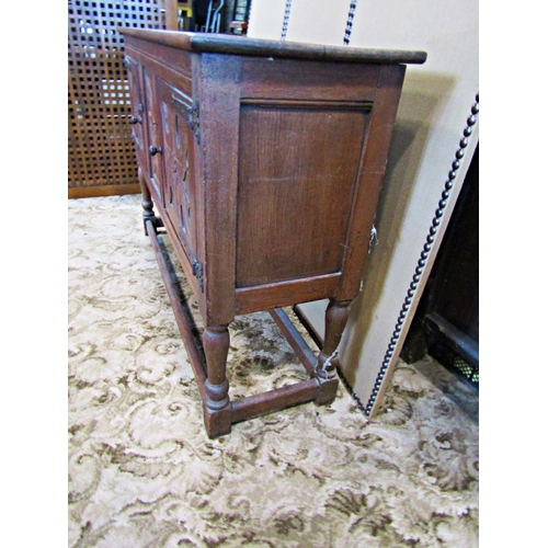 2335 - A rustic carved oak sideboard enclosed by two panelled doors with ironwork hinges on turned supports... 