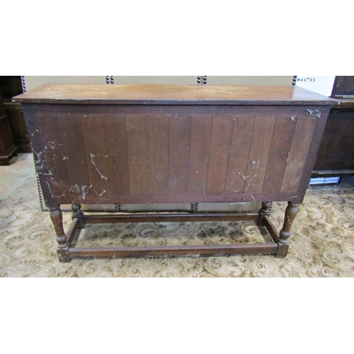 2335 - A rustic carved oak sideboard enclosed by two panelled doors with ironwork hinges on turned supports... 