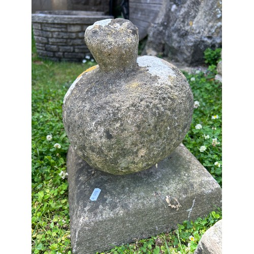 2083A - A weathered natural carved stone finial raised on a square tapered cap, 32 cm high